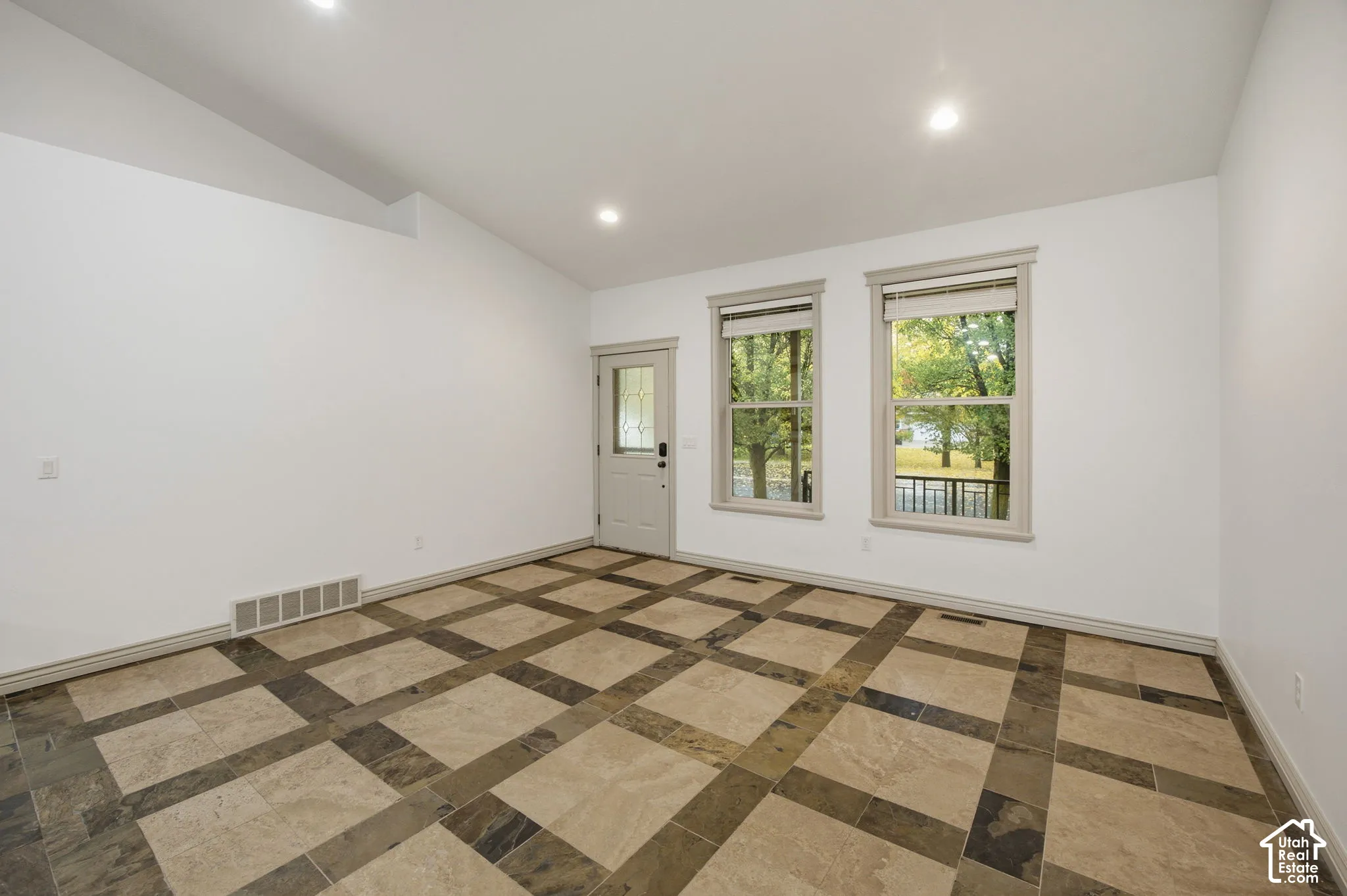 Vaulted ceiling featuring recessed lighting, large-format tile flooring with a geometric grid pattern, and double windows with neutral trim