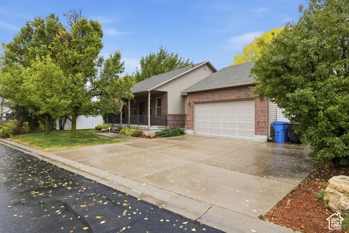 Single-story exterior featuring brick and siding facade, covered front porch with metal railing, attached two-car garage, and concrete driveway