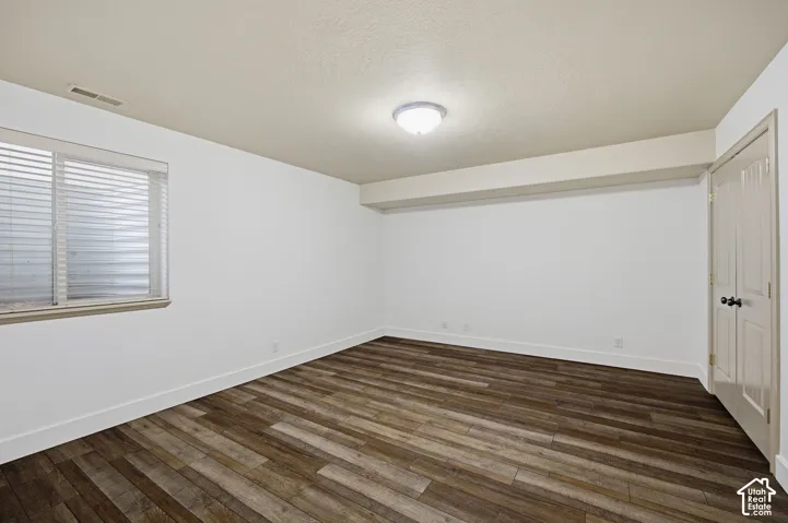 Room featuring neutral wall paint, wood-finish flooring, a recessed window, and double-panel doors