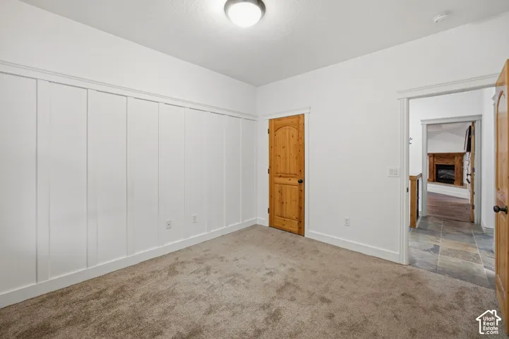 Room featuring wall-to-wall carpeting, white board-and-batten wall detailing, and a solid wood arched door