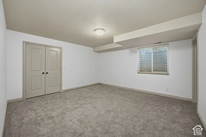 Neutral-toned room featuring wall-to-wall carpeting, double-panel interior doors, and a window with horizontal blinds