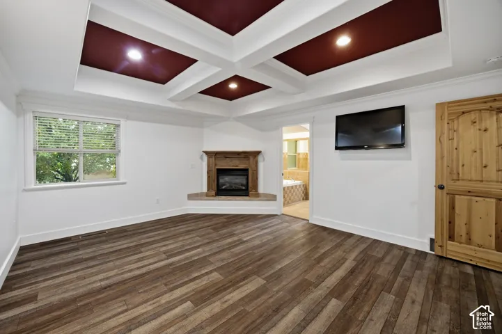 Coffered ceiling featuring recessed lighting, corner fireplace with a wood mantel, wood-finish flooring, and a natural wood-finish interior door