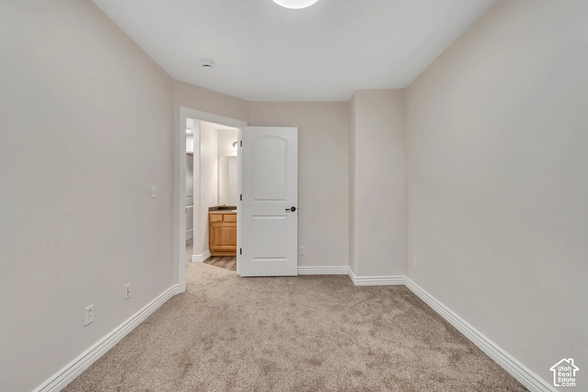 Interior space featuring neutral wall tones, wall-to-wall carpeting, and a single-panel arch-top interior door