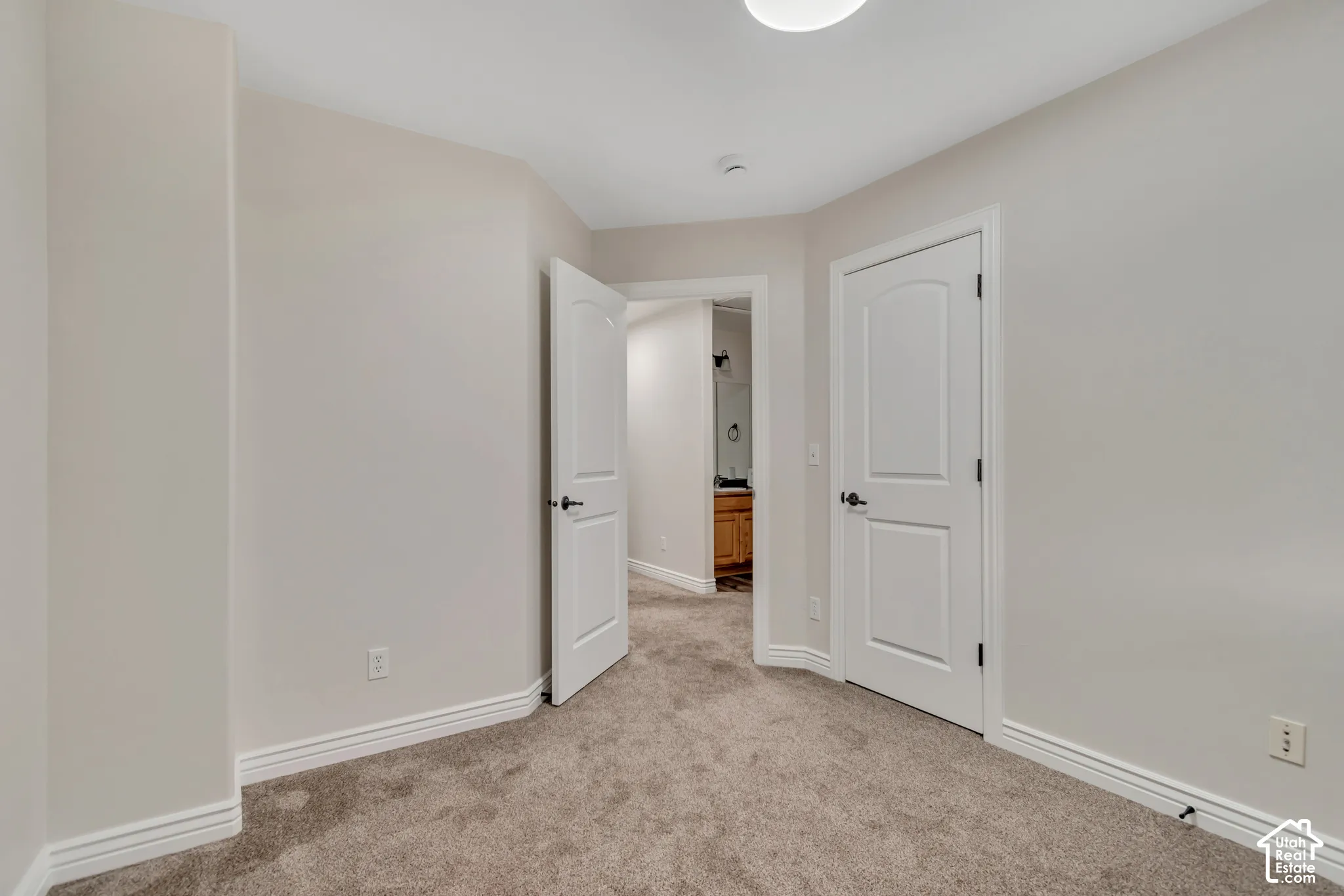Neutral wall tones, wall-to-wall carpeting, and two solid-core doors with arched-panel detailing