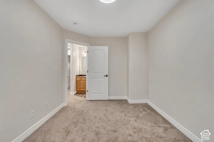 Interior space featuring neutral wall tones, wall-to-wall carpeting, and a single-panel arch-top interior door
