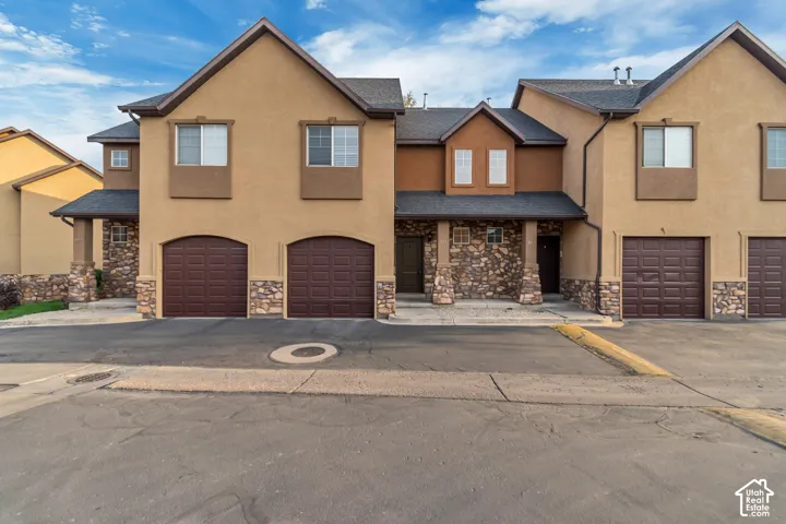 Multi-unit exterior featuring stucco siding, stone veneer accents, multi-gabled rooflines, and multiple attached garages