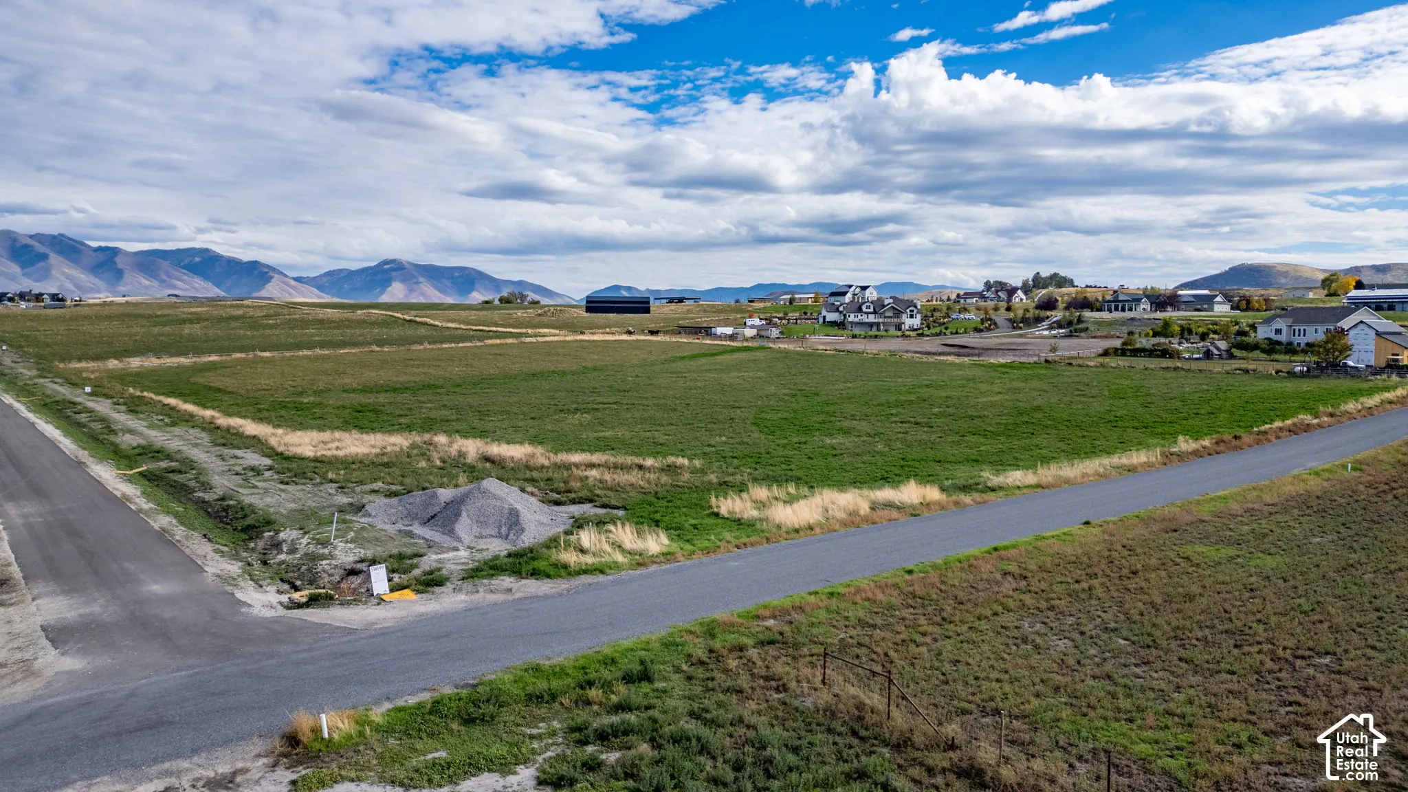 Expansive undeveloped land parcel featuring paved street access, open terrain, and mountain backdrop