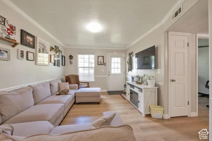 Living area featuring wood-finish flooring, crown molding, chair rail trim, and a multi-lite exterior entry door