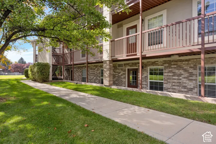 Multi-story exterior featuring a brick facade, concrete walkway, metal balcony railings, and exterior staircases