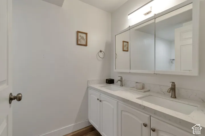 Double vanity with white cabinetry, stone-finish countertops, dual under-mount sinks, brushed nickel faucets, and a large multi-panel medicine cabinet