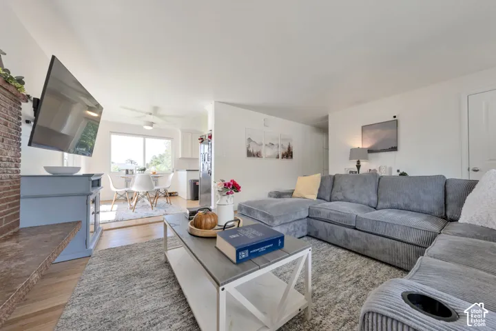 Living area featuring a brick fireplace, wood-finish flooring, and a ceiling fan