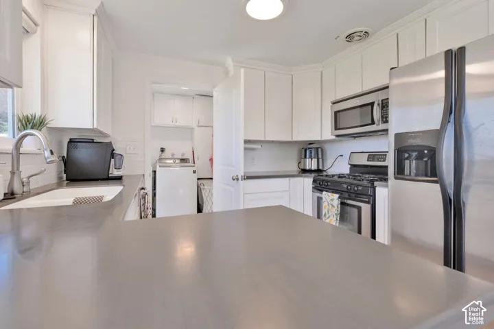 Kitchen featuring white shaker cabinetry, stainless steel appliances, solid surface countertops, and a subway tile backsplash