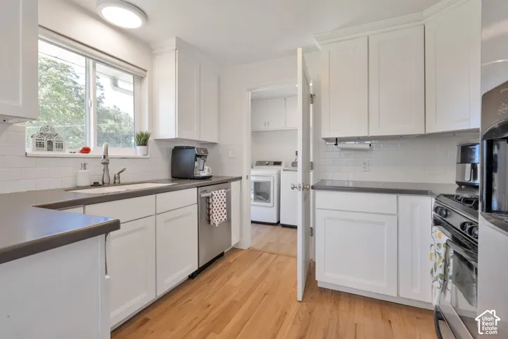U[dated kitchen featuring white shaker-style cabinetry, solid-surface countertops, subway tile backsplash, stainless steel dishwasher, and wood-flooring