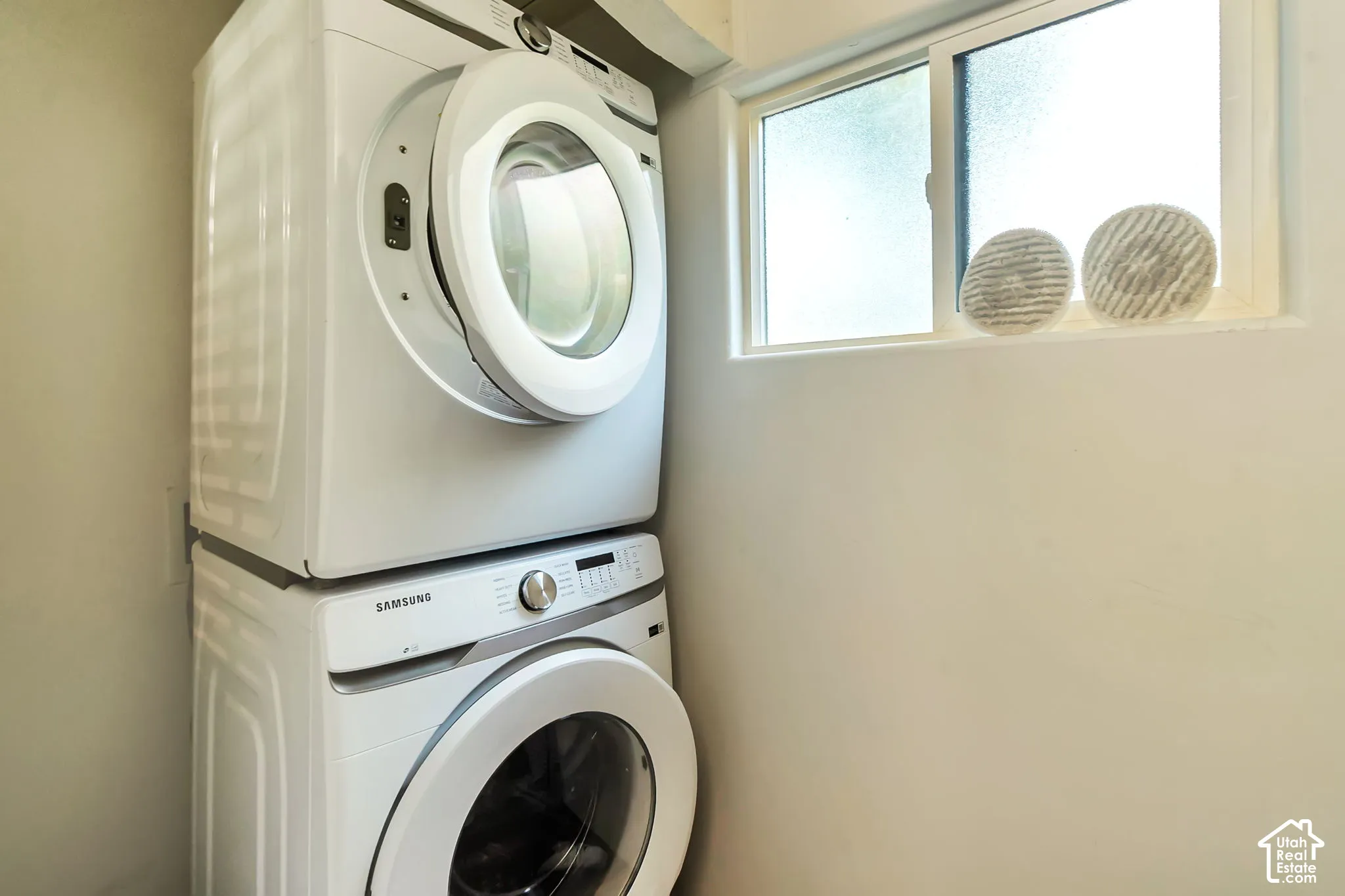 Stacked white laundry appliances featuring front-loading doors and a horizontal sliding window