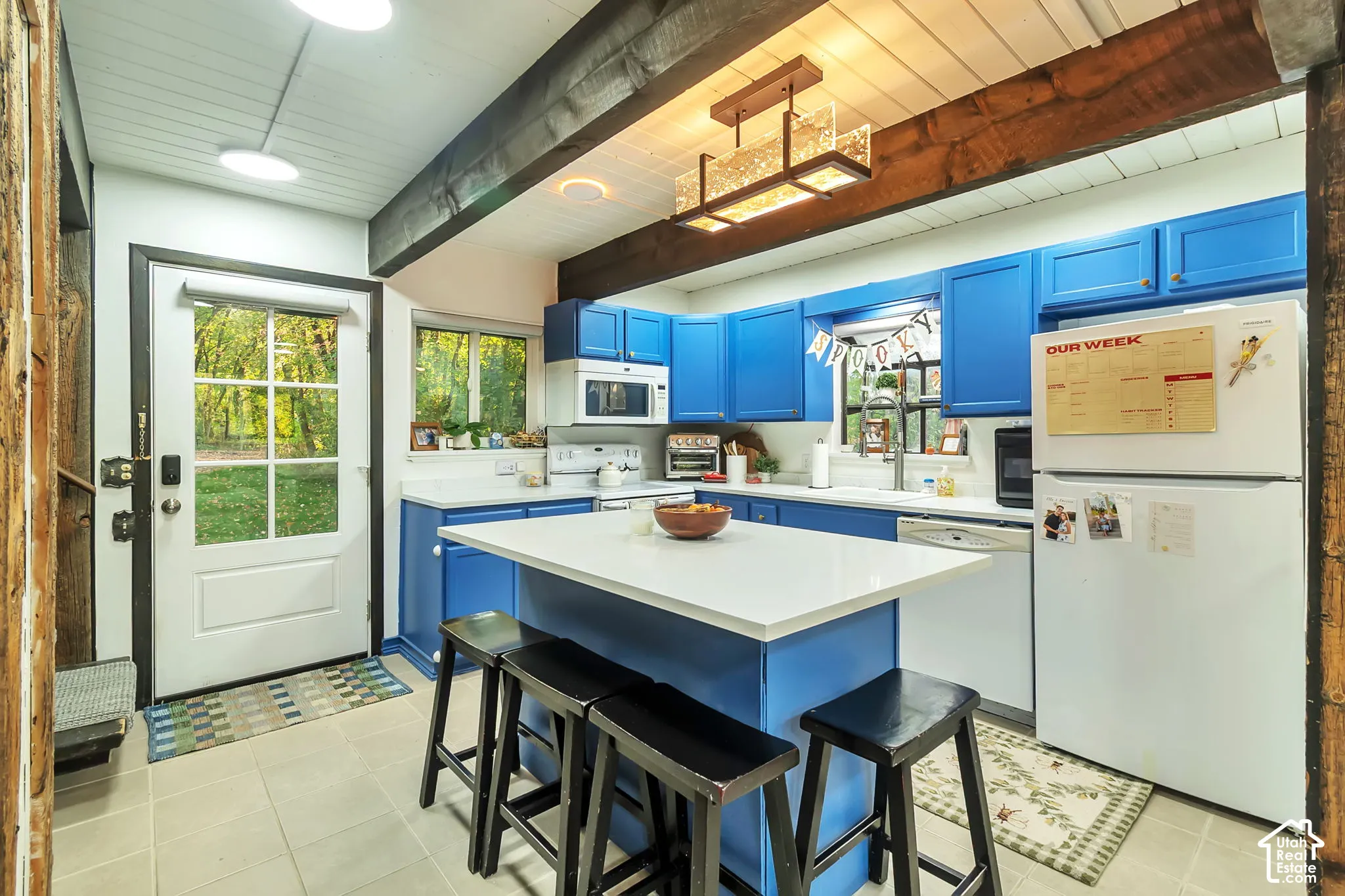 Kitchen featuring an island with a quartz countertop, exposed wooden ceiling beams, beadboard ceiling, and cabinetry with metal hardware