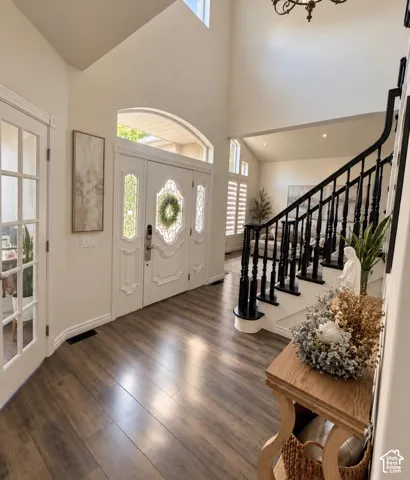 Foyer featuring vaulted ceilings, wood-finish flooring, double entry doors with glass detailing, and a staircase with a black handrail and balusters