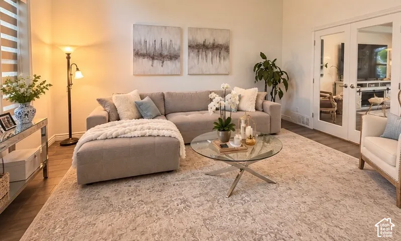 Living area featuring high ceilings, wood-finish flooring, dual-pane windows with integrated blinds, and French doors with glass inserts