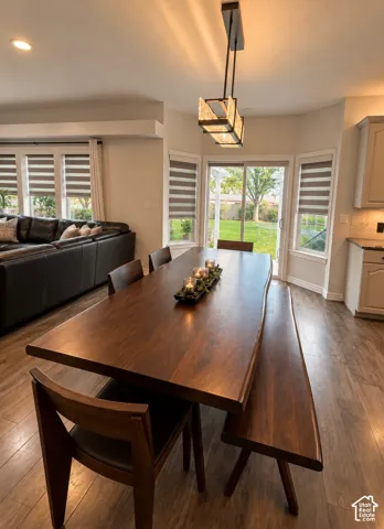 Dining area featuring wood-finish flooring, a geometric multi-light pendant fixture, sliding glass doors, and a bay window configuration