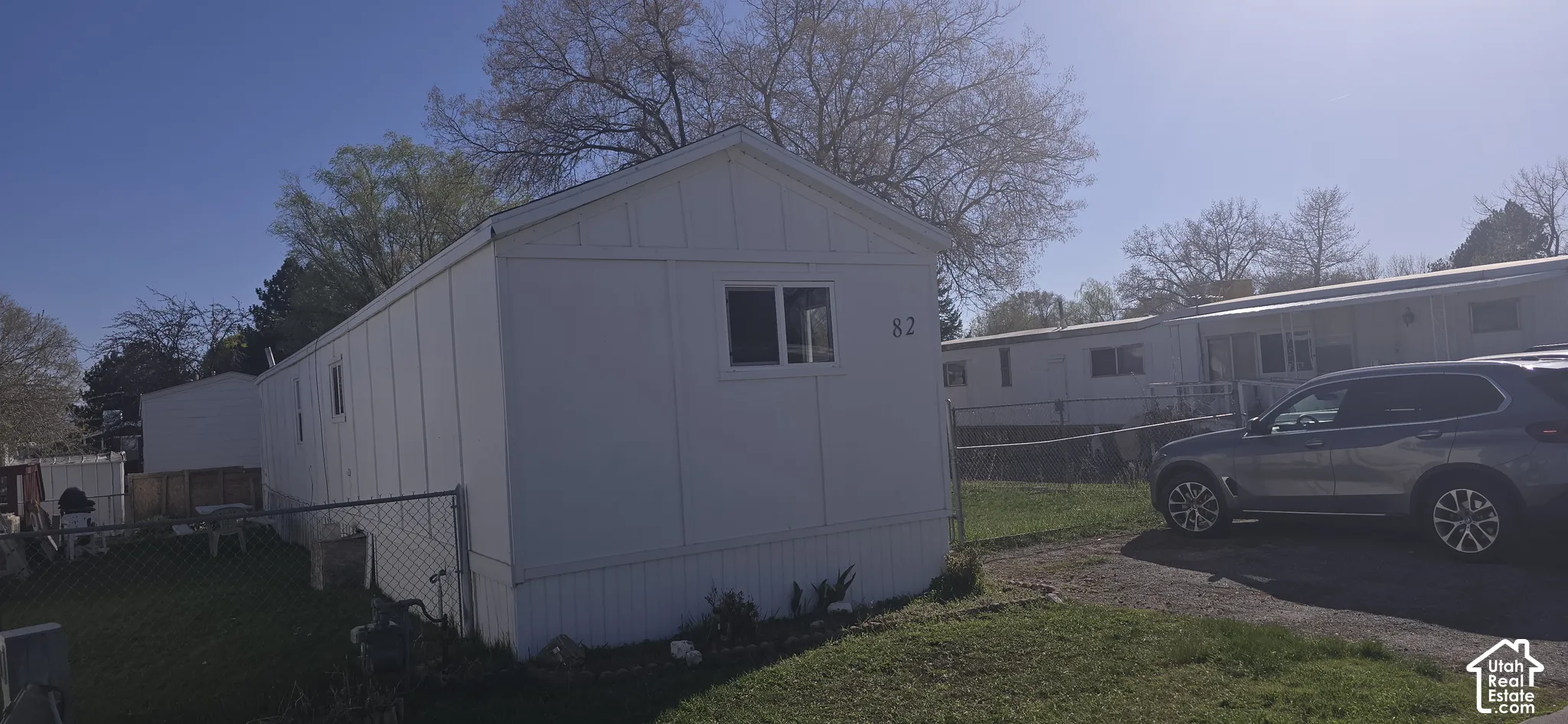 Single-level exterior featuring vertical panel siding, a gable roofline, and chain-link perimeter fencing