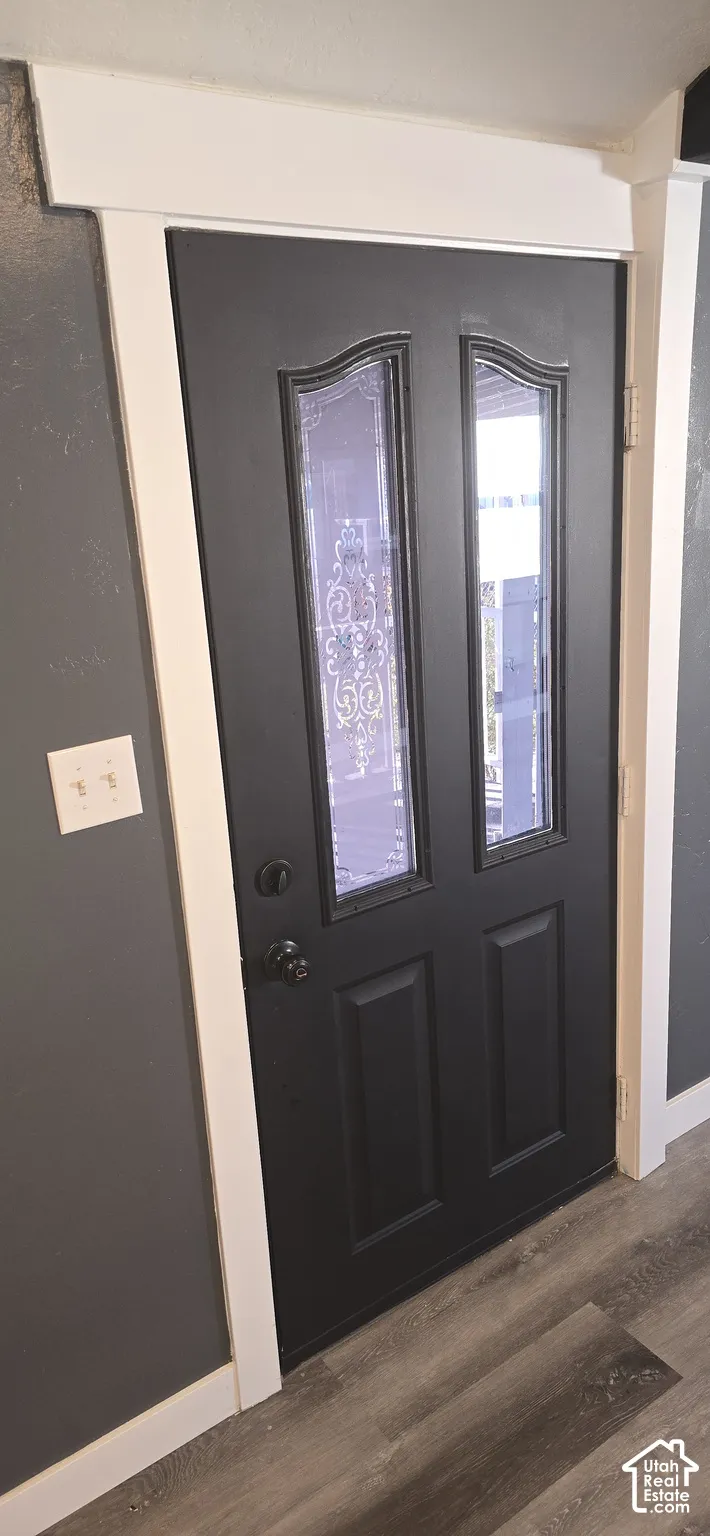 Dark-finished door with dual glass panels, decorative leaded glass inserts, and black hardware, framed by high-contrast white trim