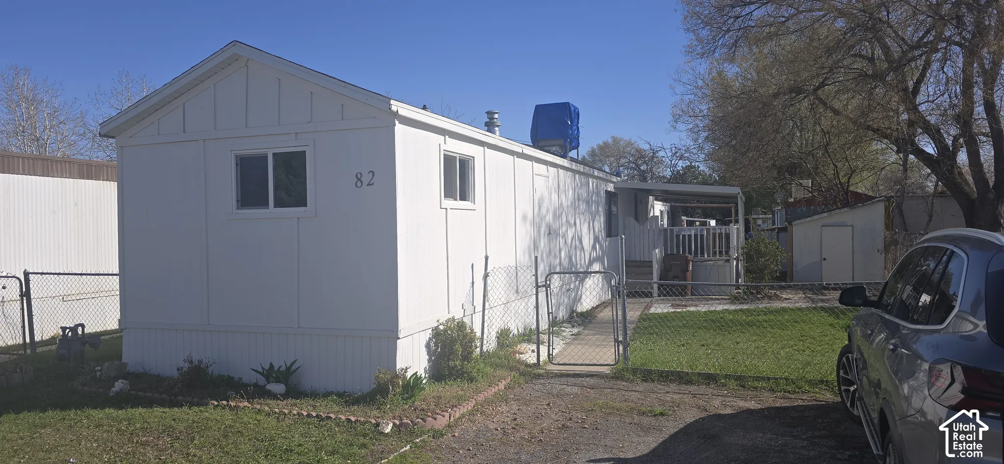 Exterior featuring white siding, a metal-framed fence, a detached storage structure, and a covered porch
