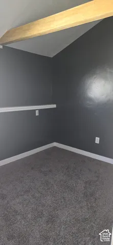 Interior space featuring a vaulted ceiling with an exposed wood beam, wall-to-wall carpeting, and a chair rail