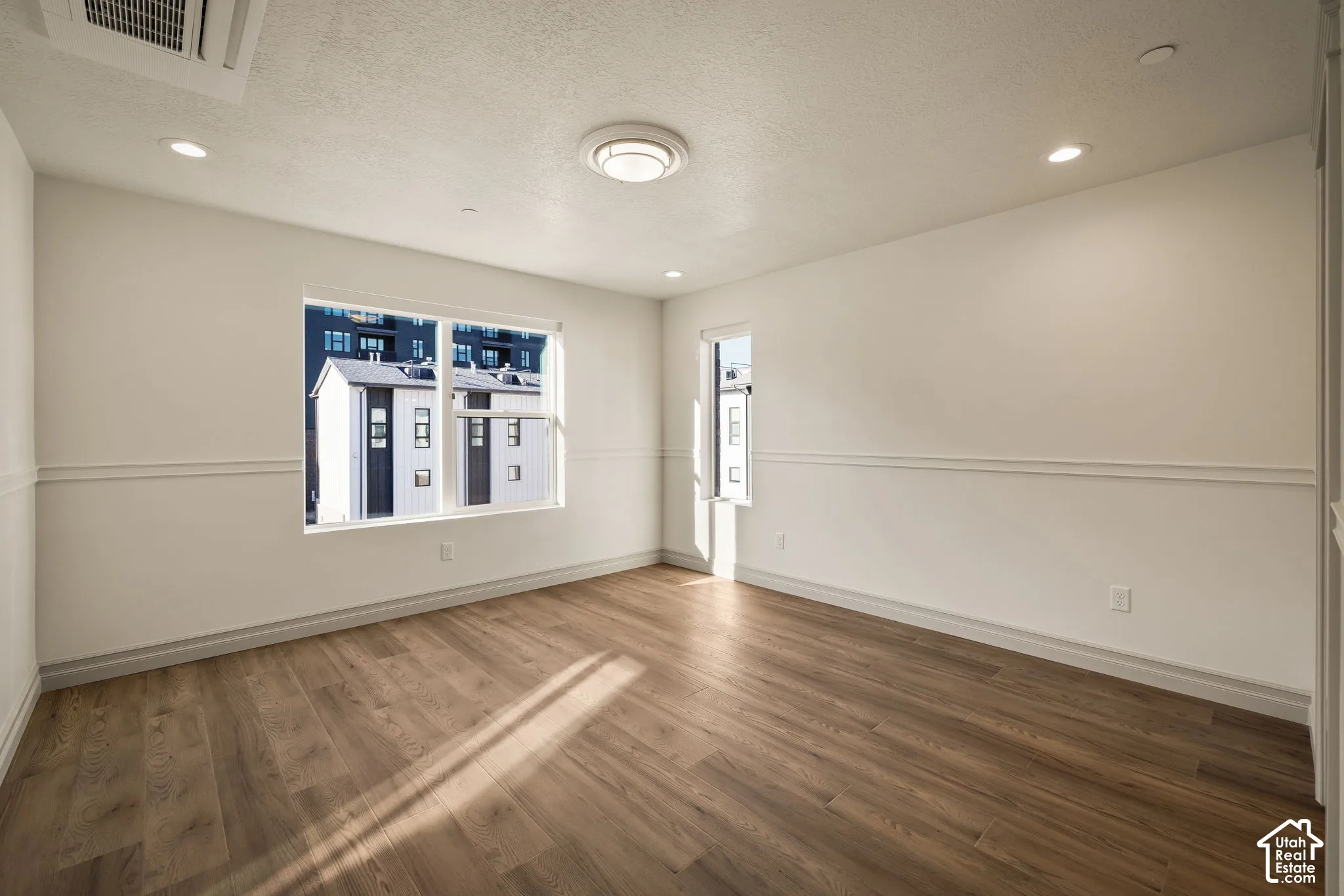 Room featuring wood-finish flooring, recessed lighting, wall-mounted ceiling light fixture, multi-pane windows, and chair rail millwork