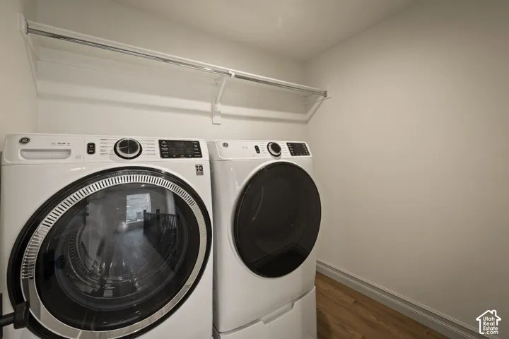 Laundry space featuring wood-finish flooring and a white built-in wall-mounted shelving and garment rod system