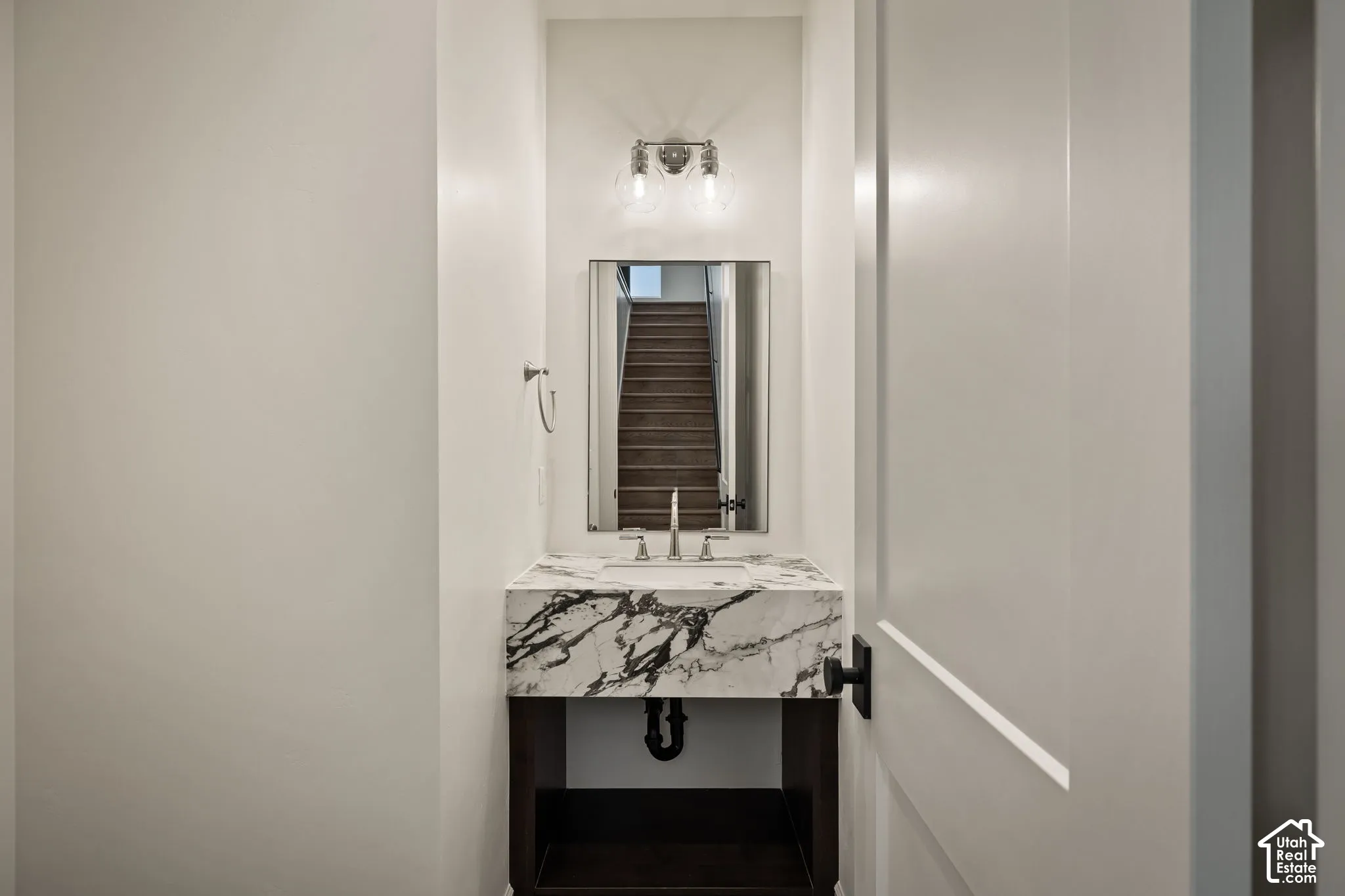 Floating stone-top vanity featuring a vessel sink, dual-light wall sconce, rectangular wall mirror, and matte black hardware