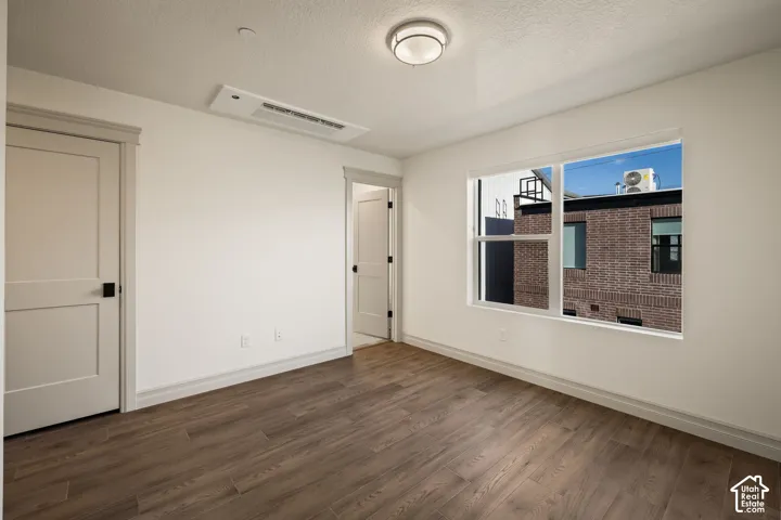 Neutral-toned interior featuring wood-finish flooring, shaker-style doors with matte black hardware, recessed ceiling lighting, and a large window