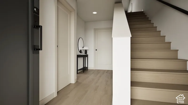 Entryway featuring wood-finish flooring, solid-core interior doors, recessed ceiling lighting, and a staircase with a white-finished half wall