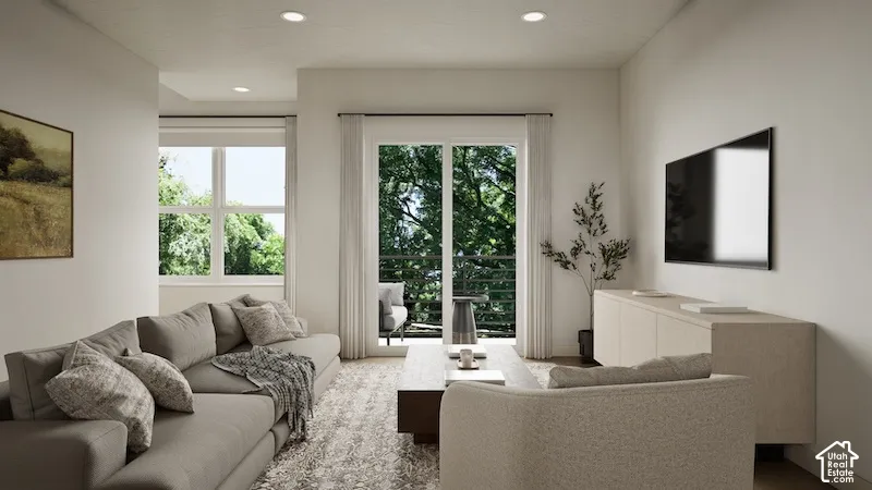 Neutral interior featuring recessed lighting, a sliding glass door with a balcony, and abundant natural light from multiple window placements