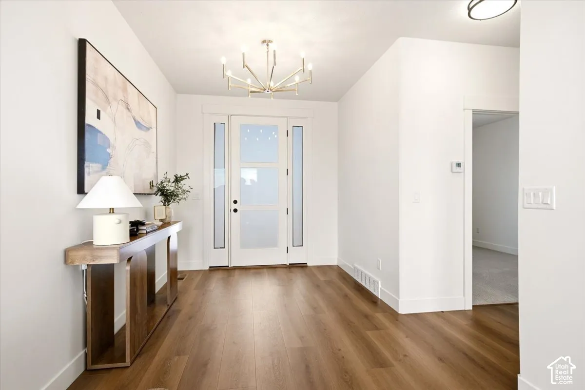 Entryway featuring wood-finish flooring, a multi-pane glass panel front door with sidelights, and a modern sputnik-style chandelier