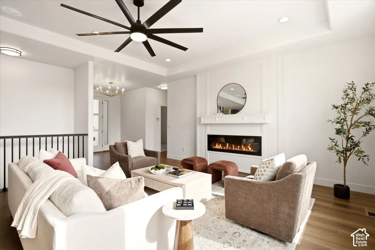 Living area featuring a coffered ceiling, linear gas fireplace with a custom mantle, recessed lighting, wood-finish flooring, and a multi-blade ceiling fan