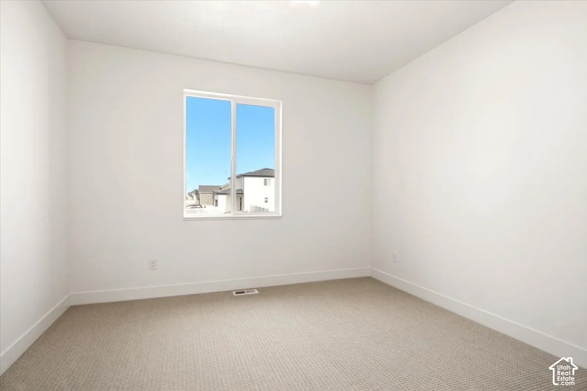 Neutral interior room featuring crisp white walls and textured carpet flooring