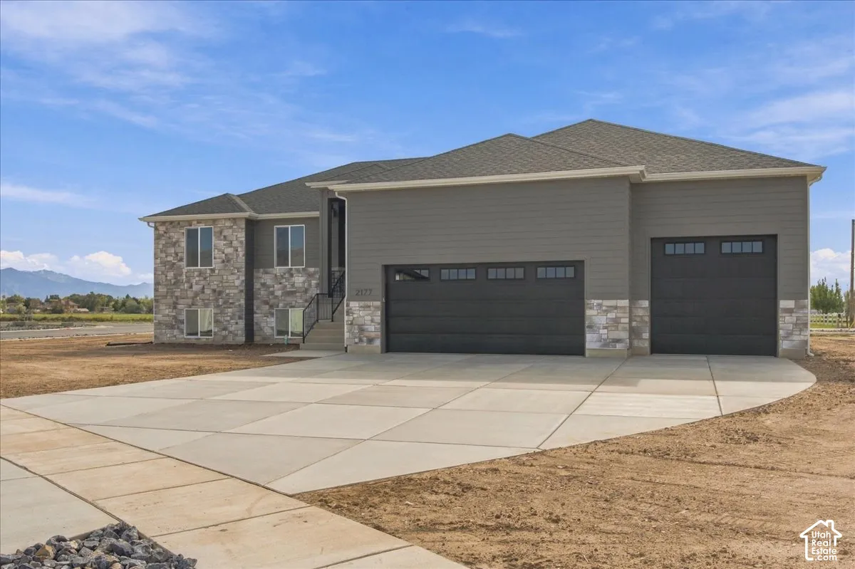 Exterior featuring lap siding, stone veneer masonry, asphalt shingle roofing, and an attached three-car garage with windows