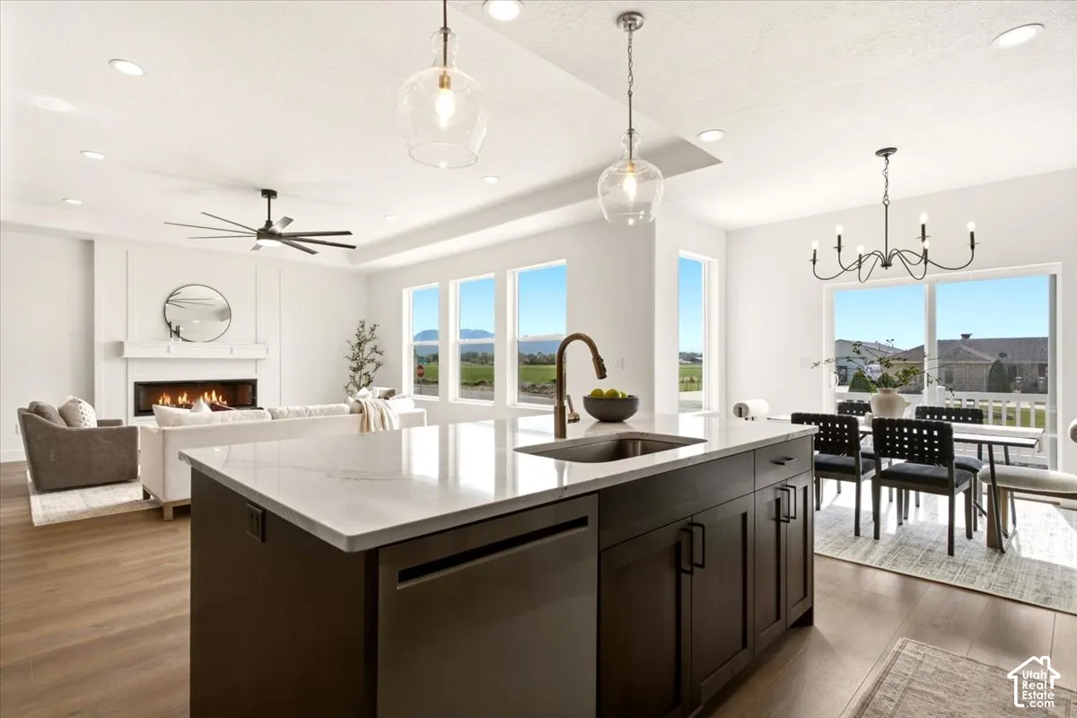 Kitchen featuring an expansive island with a light-toned solid surface countertop, undermount sink, and dark cabinetry