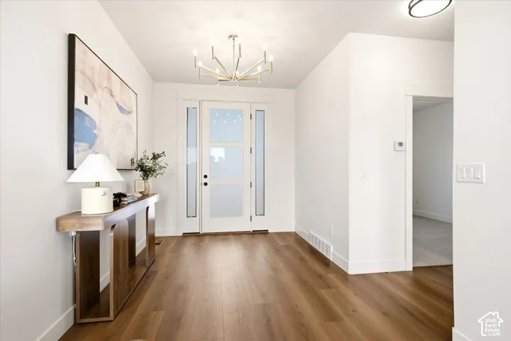 Entryway featuring wood-finish flooring, a multi-pane glass panel front door with sidelights, and a modern sputnik-style chandelier