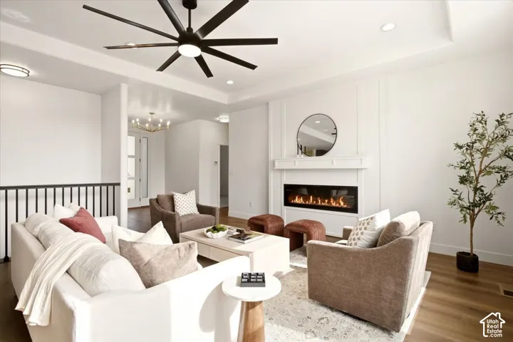 Living area featuring a coffered ceiling, linear gas fireplace with a custom mantle, recessed lighting, wood-finish flooring, and a multi-blade ceiling fan