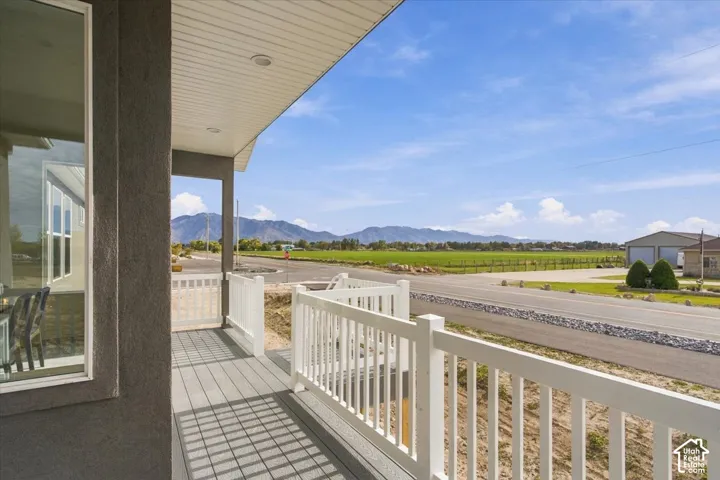 Covered porch featuring white vinyl railing, grey composite decking, recessed lighting, and mountain scenery