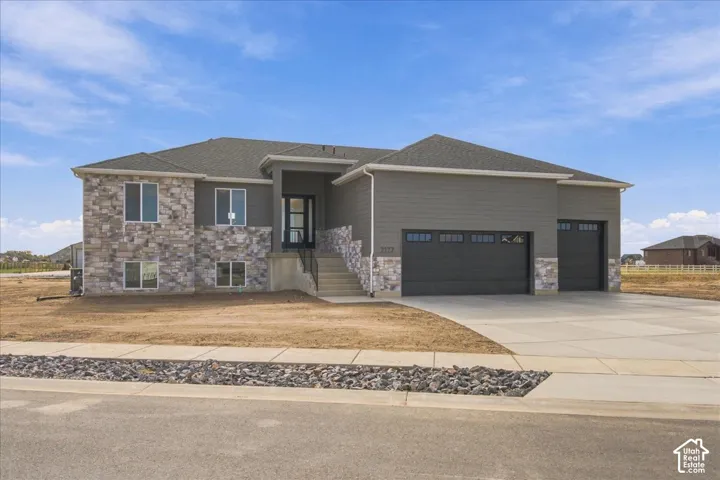 Contemporary exterior featuring horizontal siding, stone veneer accents, multi-pane windows, a concrete driveway, and an attached multi-car garage