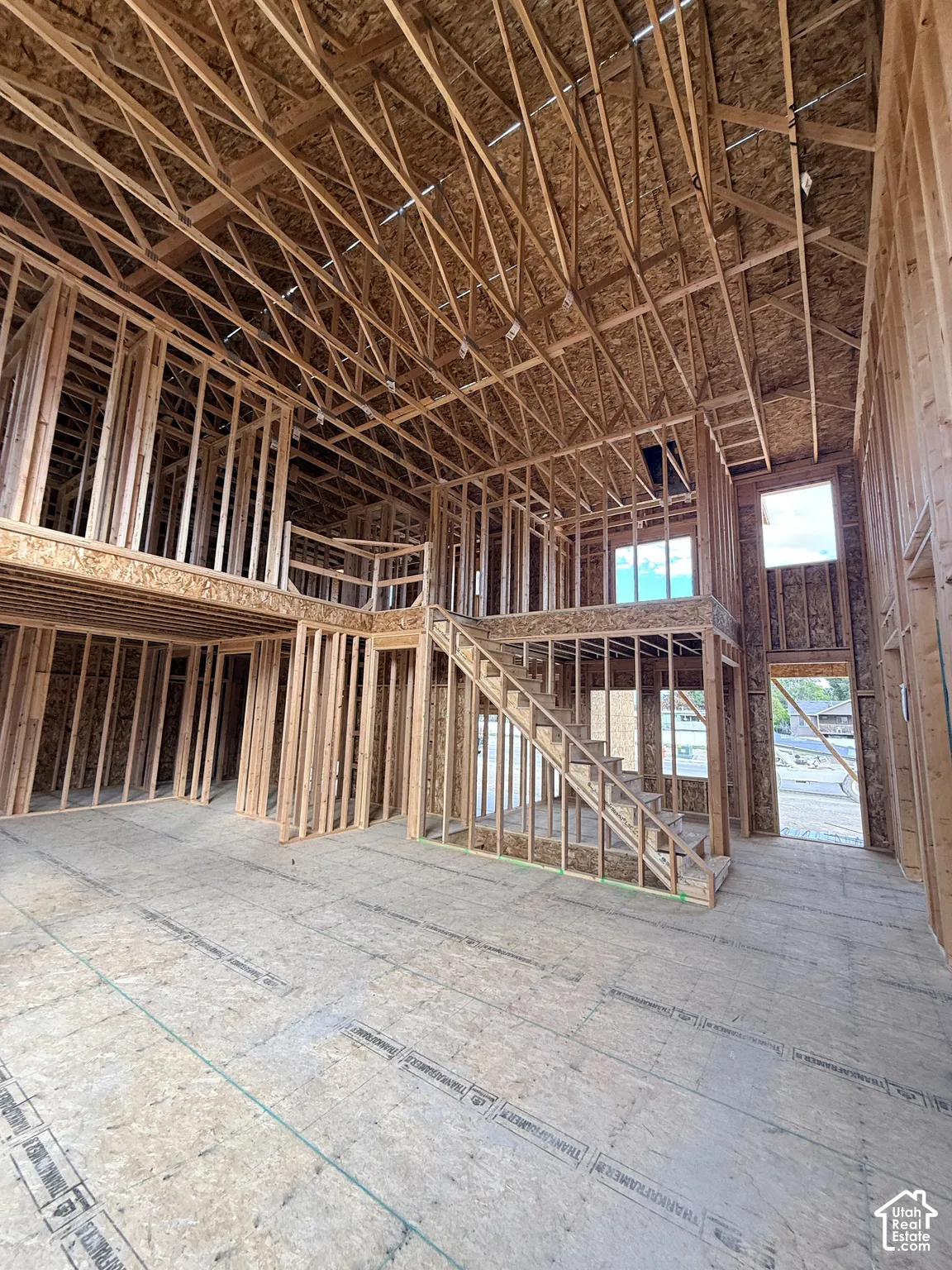 Two-story structural framing featuring exposed wood trusses, open-concept floor plan, mezzanine level, and timber staircase construction