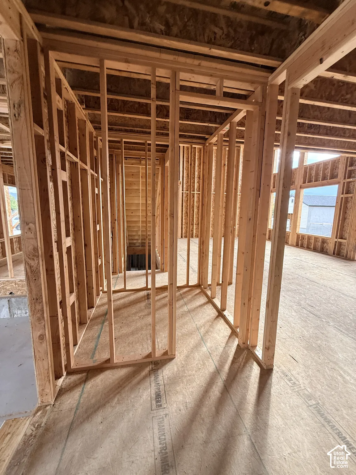 Structural wood framing featuring open floor plan construction, engineered wood subflooring, exposed vertical wall studs, and large window openings