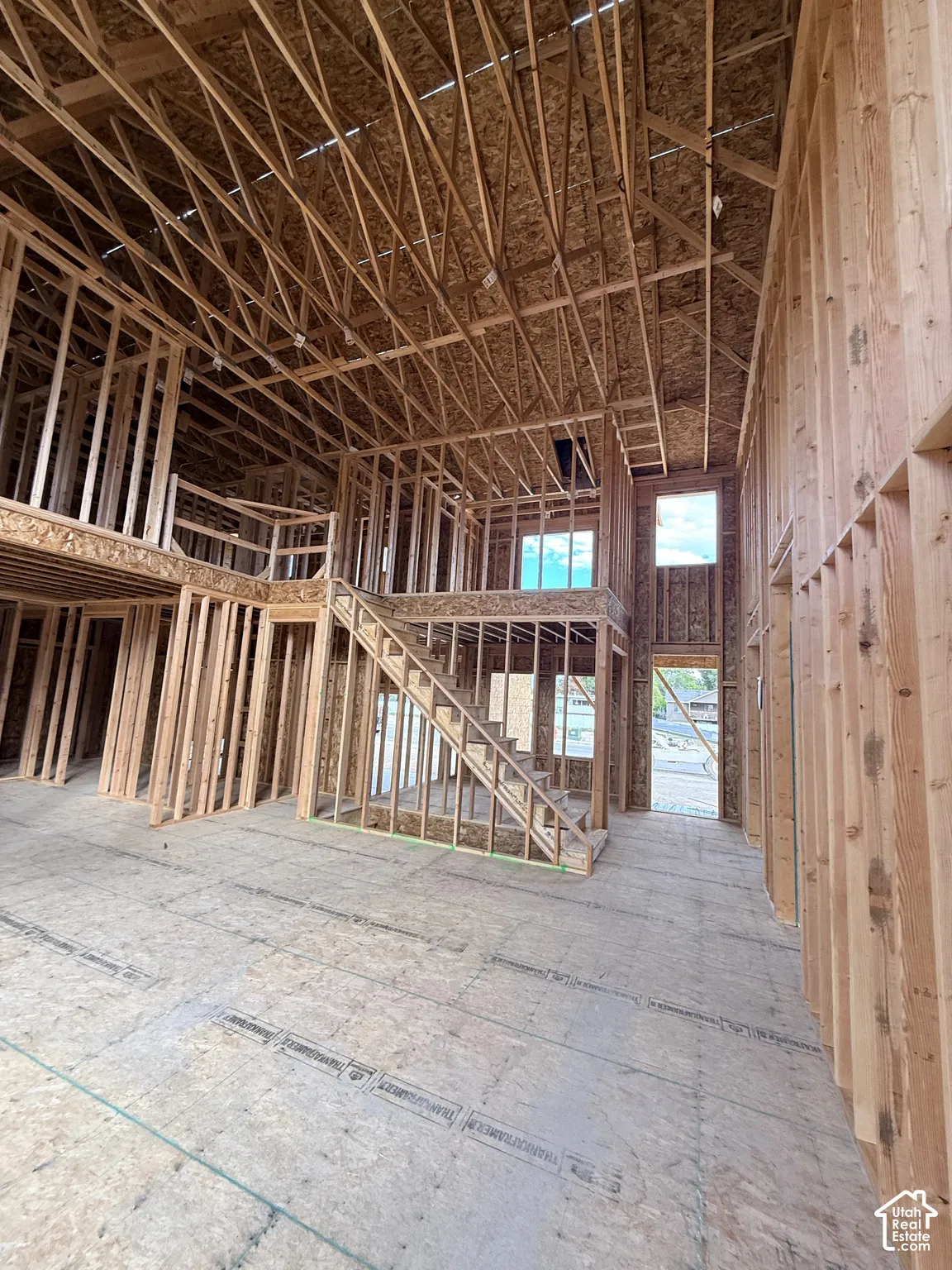 New construction framing featuring soaring vaulted ceilings, open-concept structural design, wood-truss roof system, staircase framework, and multi-level floor plan