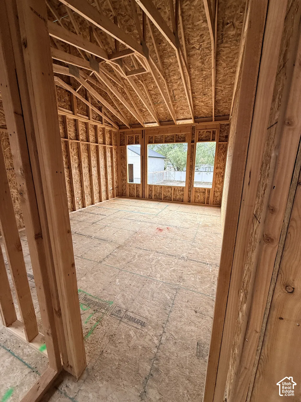 Unfinished interior space featuring exposed wood framing, vaulted ceilings, and triple-pane window openings