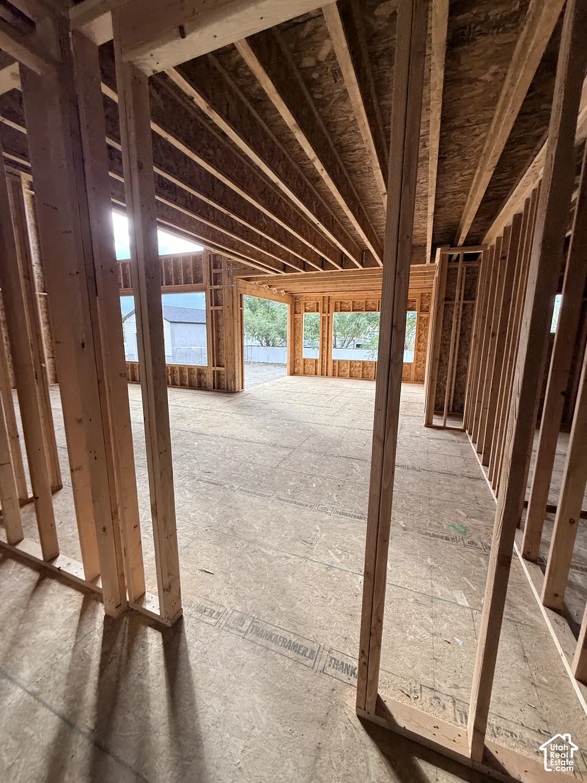 Structural wood framing featuring exposed joist ceilings, expansive window openings, and oriented strand board flooring