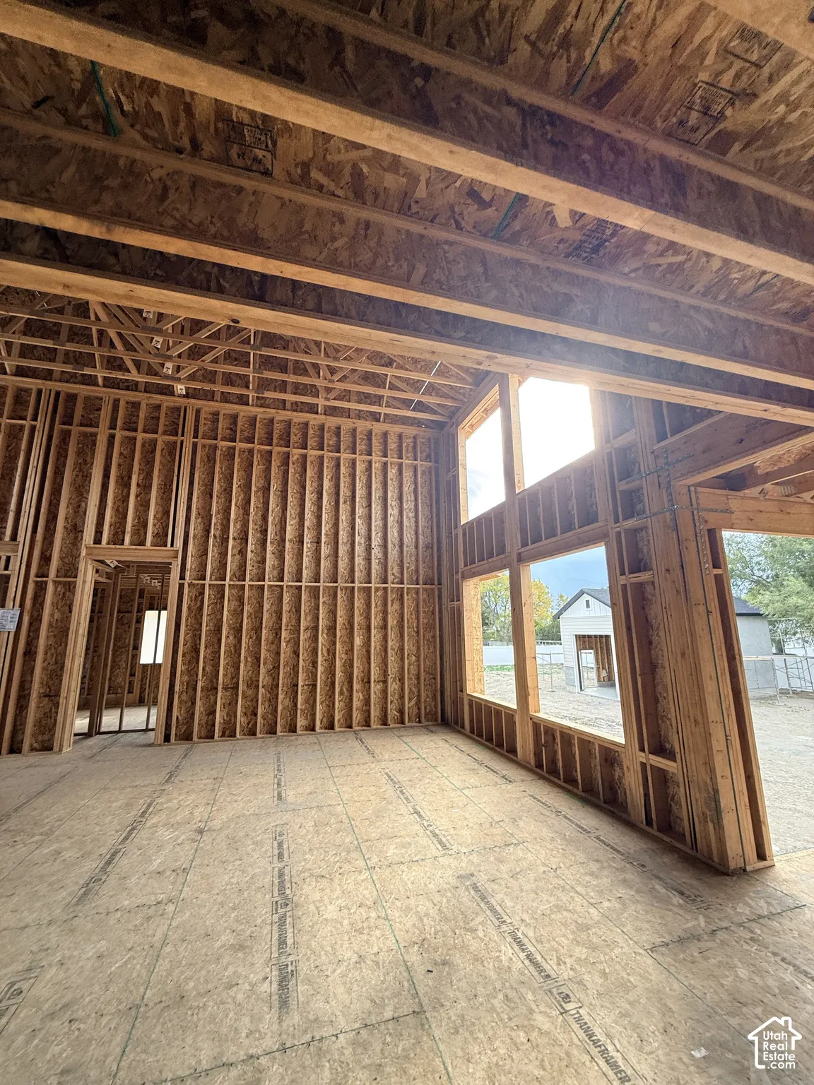 Open-concept interior framing featuring high vaulted ceilings, structural exposed timber joists, and expansive vertical window openings