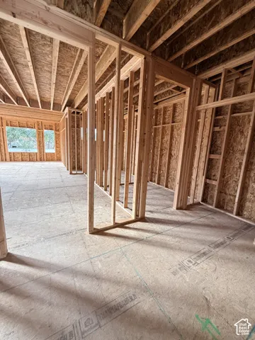Structural framing featuring exposed wood stud walls, engineered wood subflooring, and exposed ceiling joists with triple-pane window frames