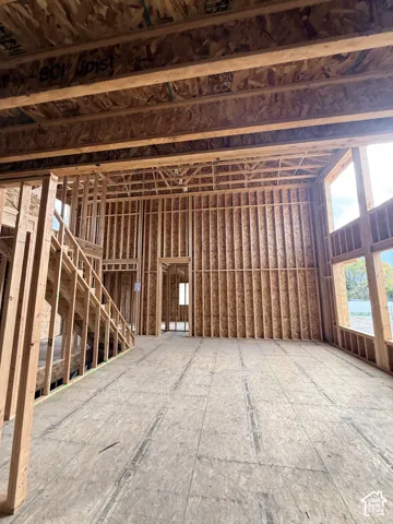 Construction in progress featuring exposed wood framing, high ceilings, structural staircase framing, and multiple window openings
