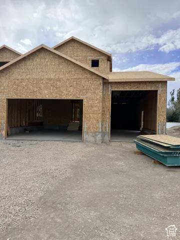New construction featuring a three-car garage configuration, wood-sheathed exterior, and concrete foundation